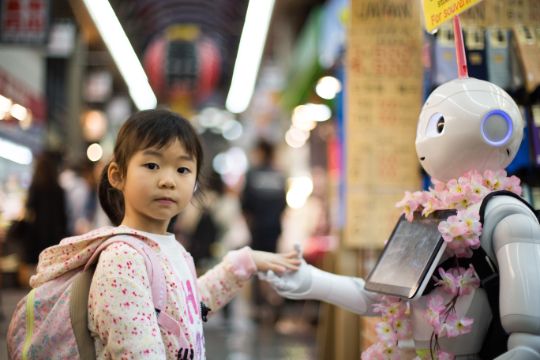 Snapshot av liten jente som holder en robots hånd