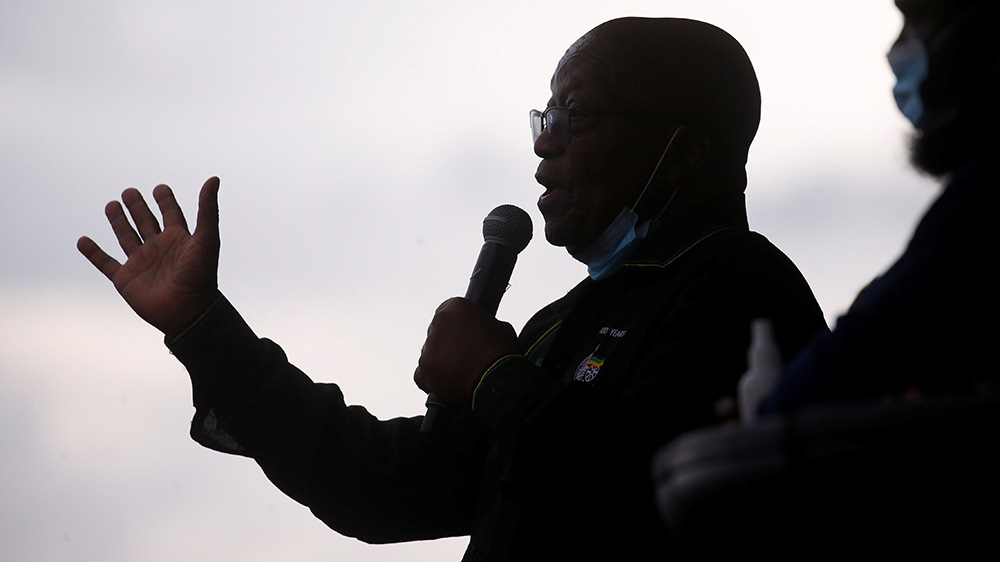 President Zuma avbilda medan han snakkar i ein mikrofon. Zuma er mørlagt, medan bakgrunnen er kvit.