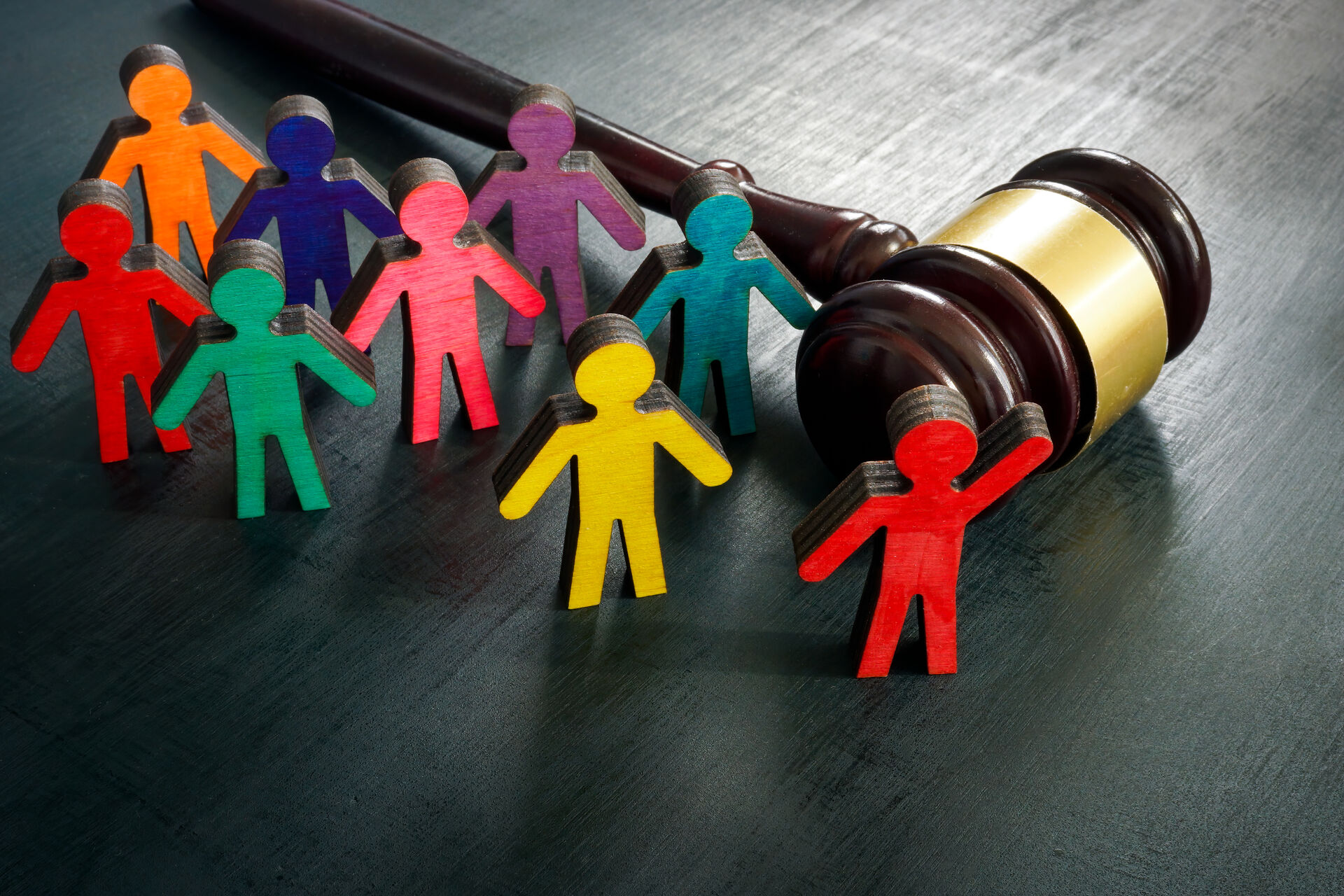 FIllustration photo of a law hammer and figures representing persons with differences.