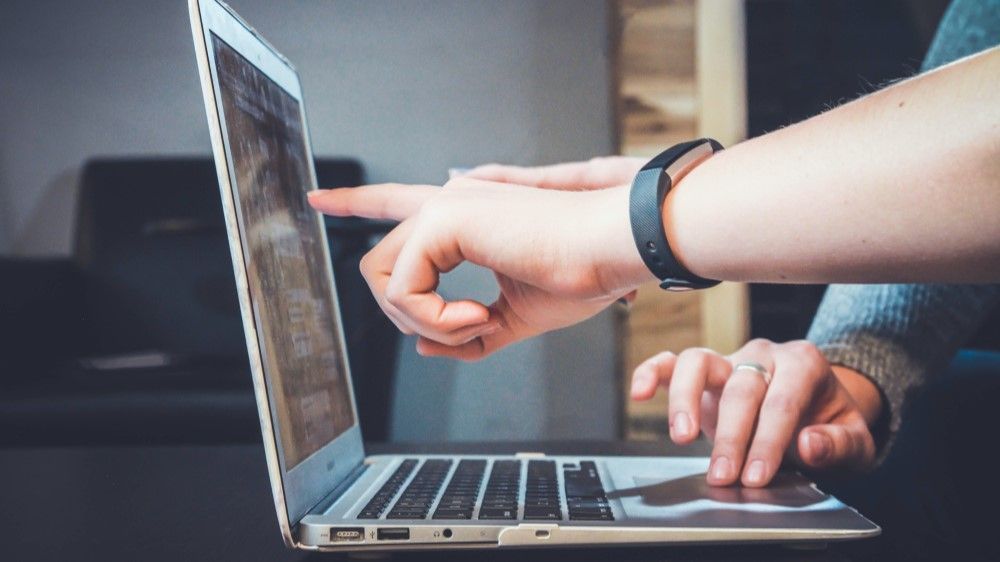 To hender som peker på en laptop