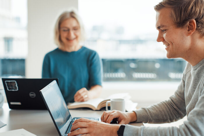 student som skriver, sittende i lyst rom