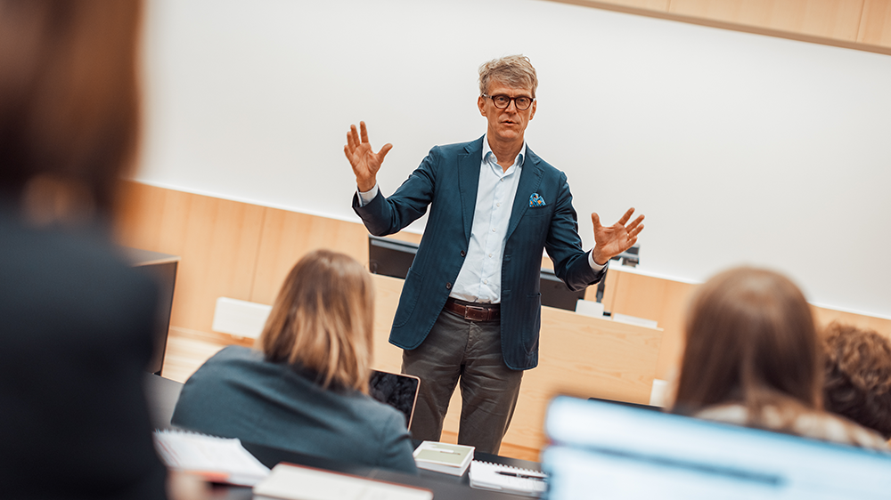 Professor Sverre Blandhol foreleser i et auditorium. Studenter sitter og hører på.