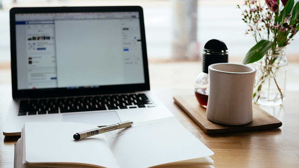 illustrasjonsbilde av laptop, notatbok og kaffekopp