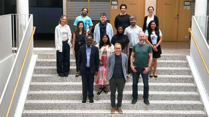 Group photo of the researchers involved in the project standing in the staircase at Domus Juridica