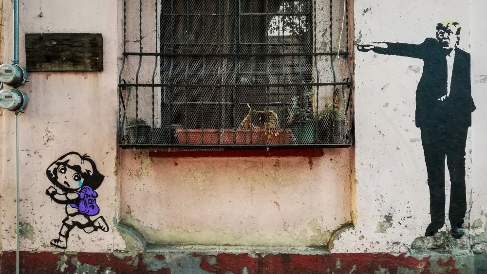 Bildet viser en husvegg og et vindu. På veggen er det et maleri av en mann og et barn.