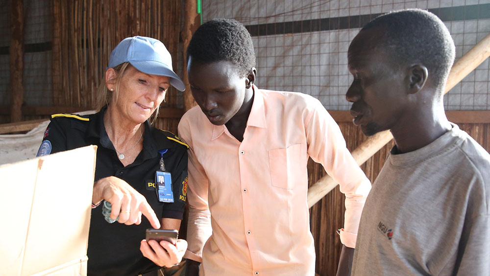A female police officer talks to young men from South Sudan.