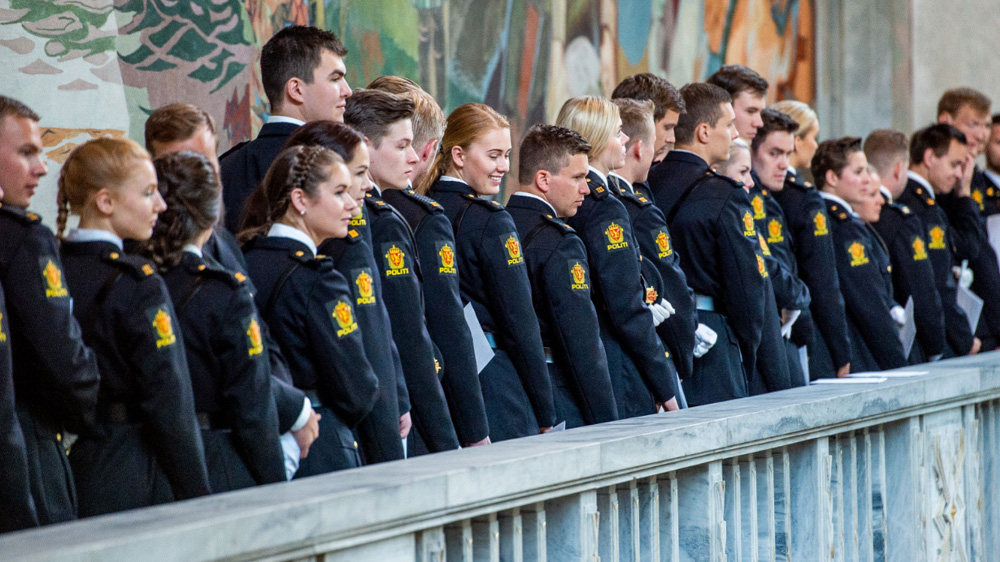 Politistudenter stående på rekke og rad i uniform i Oslo Rådhus.