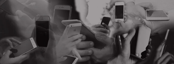 En svart-hvitt collage av flere hender som holder mobiltelefoner. 