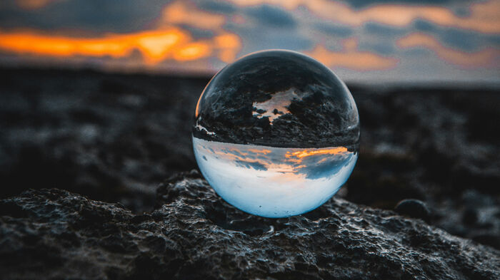 Illustrasjonbilde. Viser en glasskule som reflekterer bakken og himmelen rundt.