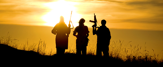 Three fighters, seen as shadows, holding weapons in the sunset. 