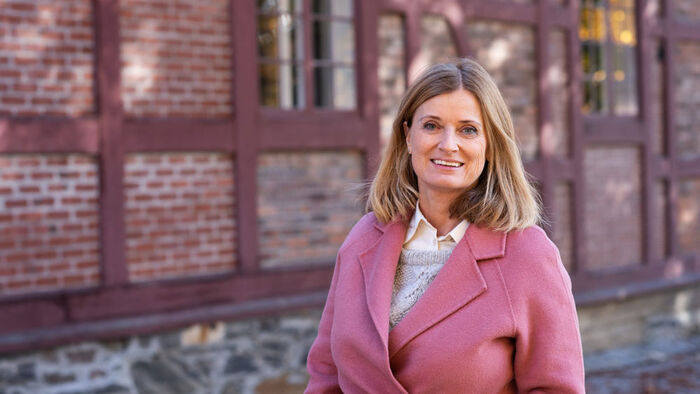 Hanne Harlem utendørs foran et murbygg.