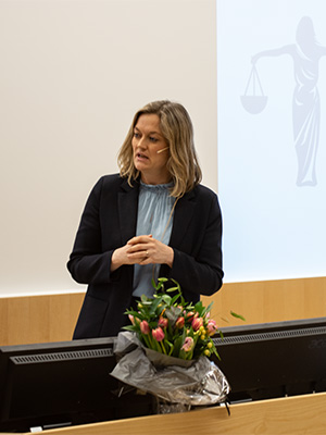Kvinne snakker foran forsamling.