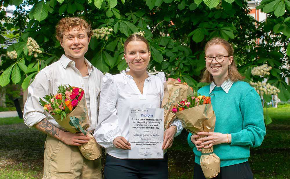 Bilde av tre personer med diplom og blomster