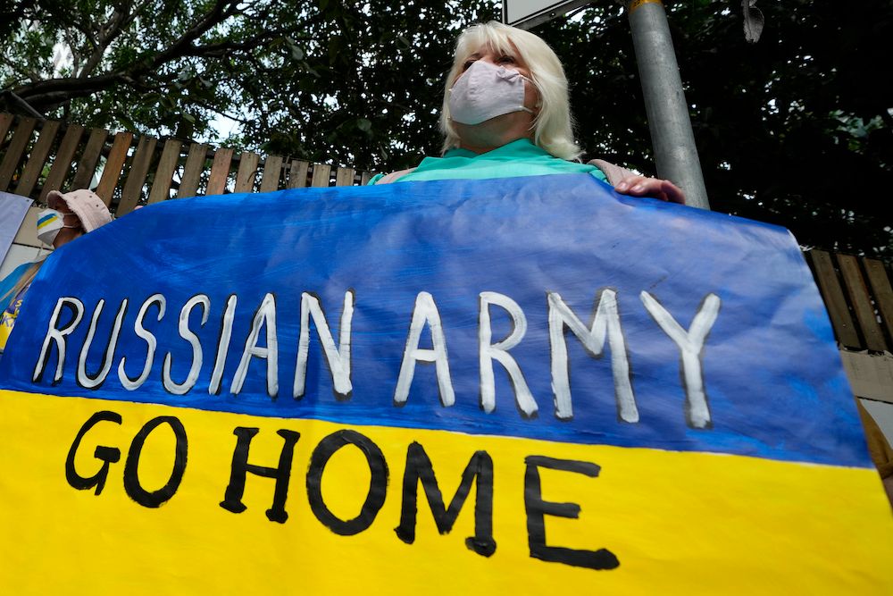 Demonstrant med Ukrainsk flagg med påskrift "Russian Army Go Home"