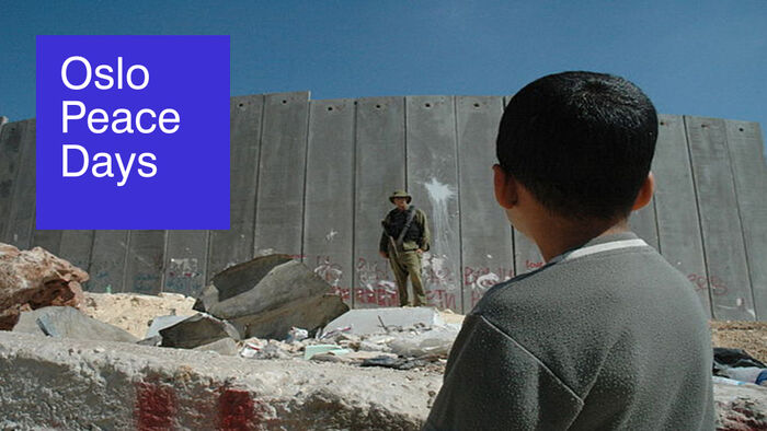 A Palestinian boy looking at a armed israeli solider