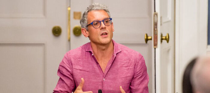 A man with glasses talking in a lecture