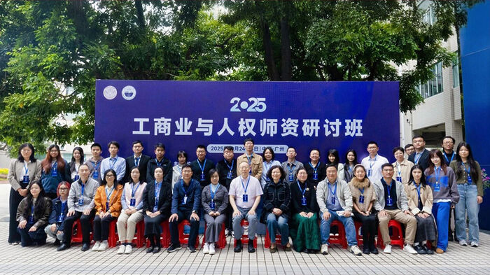 Group photo of participants in front of large banner. Outside.