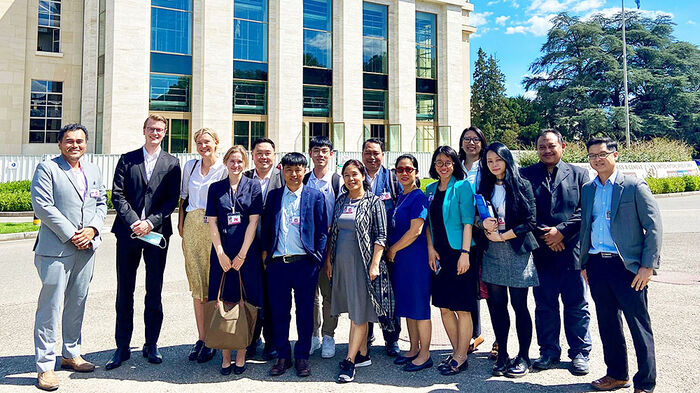 Group photo of the participating academics in front of UN building, dressed formally.