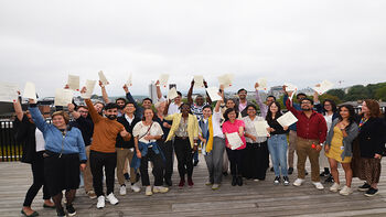 Group picture of articipants from the 2023 course holding their certificates up in the air