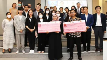 Group photo of the panel participants, two of them holding cheques with the prize reward on them