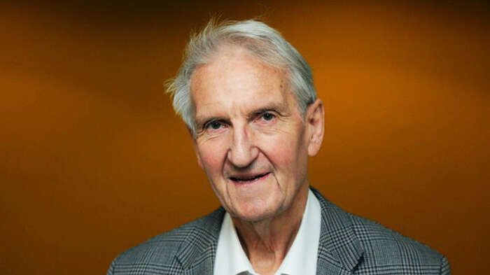 Portrait of Asbjørn Eide, shoulders up. Orange background.