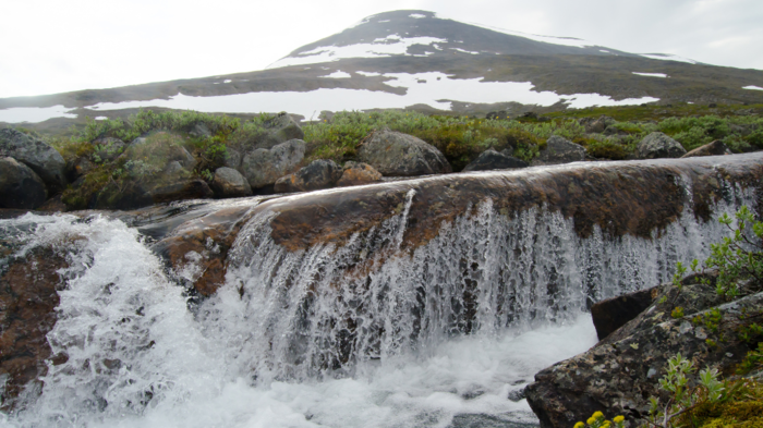 Waterfall and Rasttigaisa mountain covered in snow.