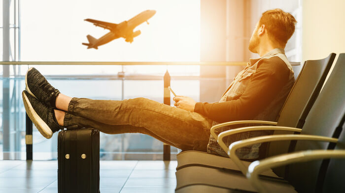 En mann sitter i venteomr?det p? en flyplass. Illustrasjonsbilde.